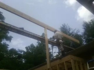 Carpenter setting a ridge beam over a new addition frame — Ice Dam Removal by Roofing Brothers in Winter Park