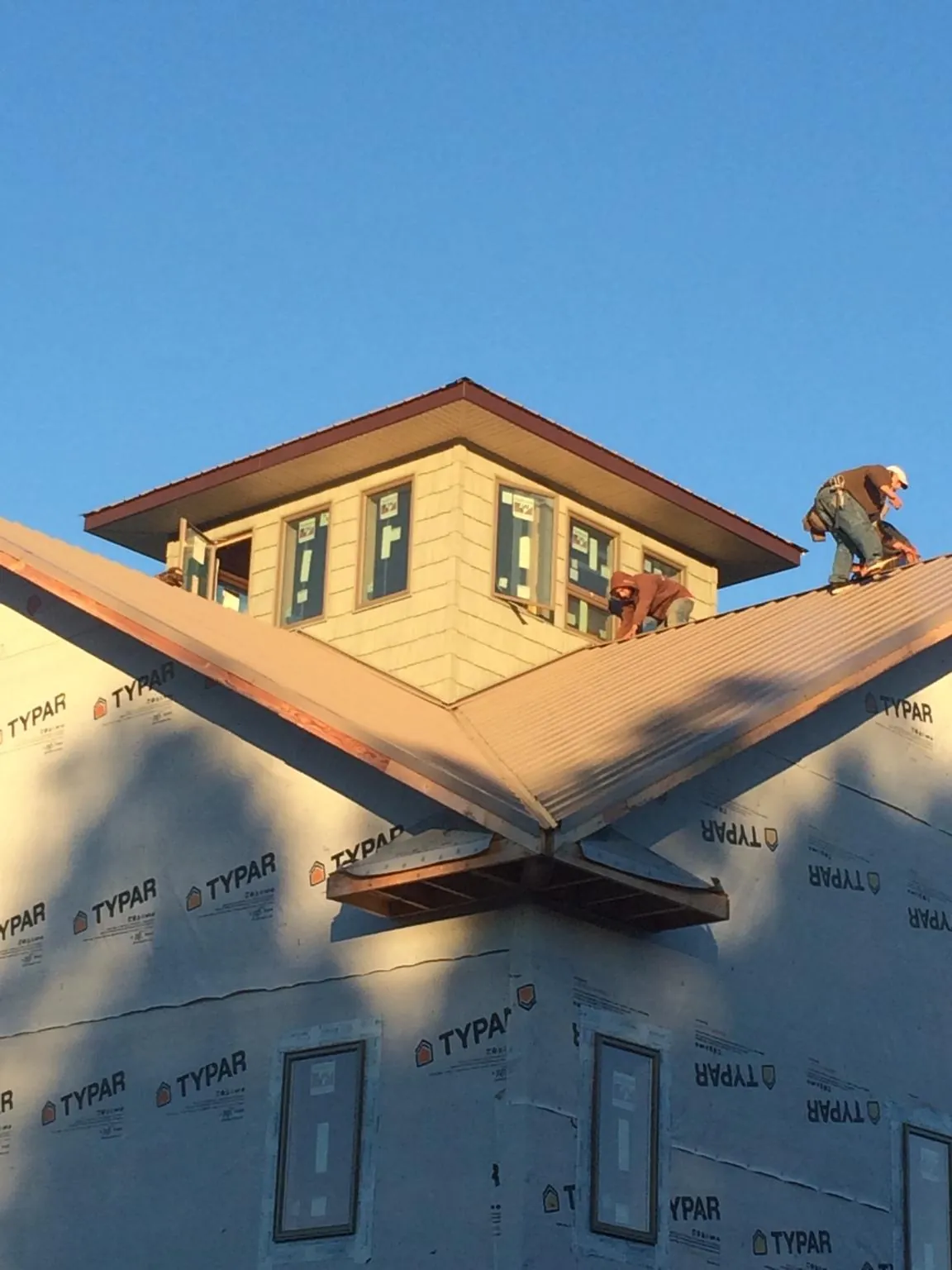 Roofers working around a rooftop cupola on a new metal roof at sunset — Roof Waterproofing in Winter Park by Roofing Brothers